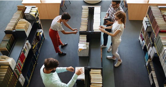 students-gathered-around-books-in-library